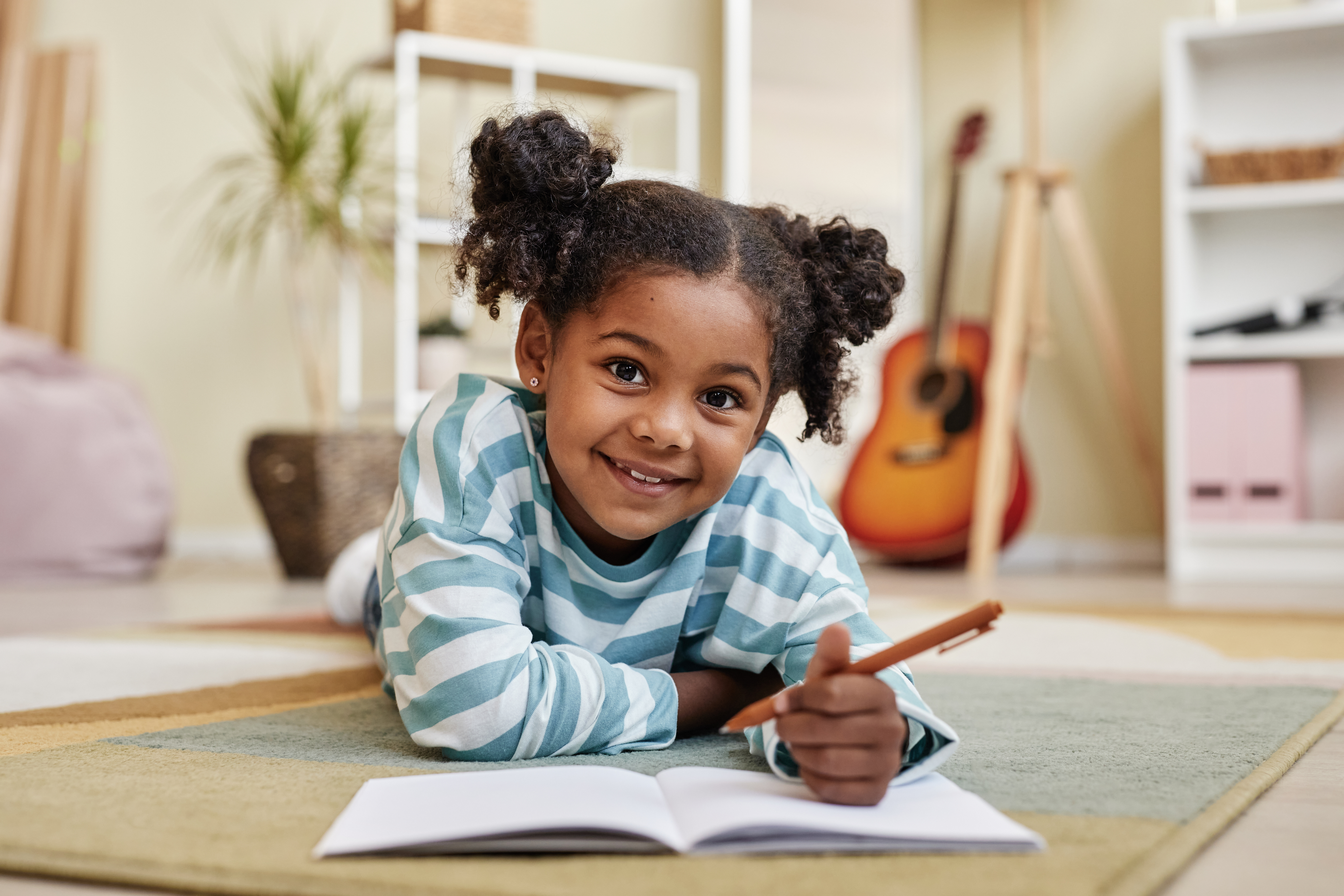 black girl writing in journal on floor