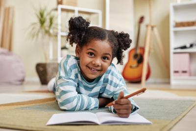black girl writing in journal on floor